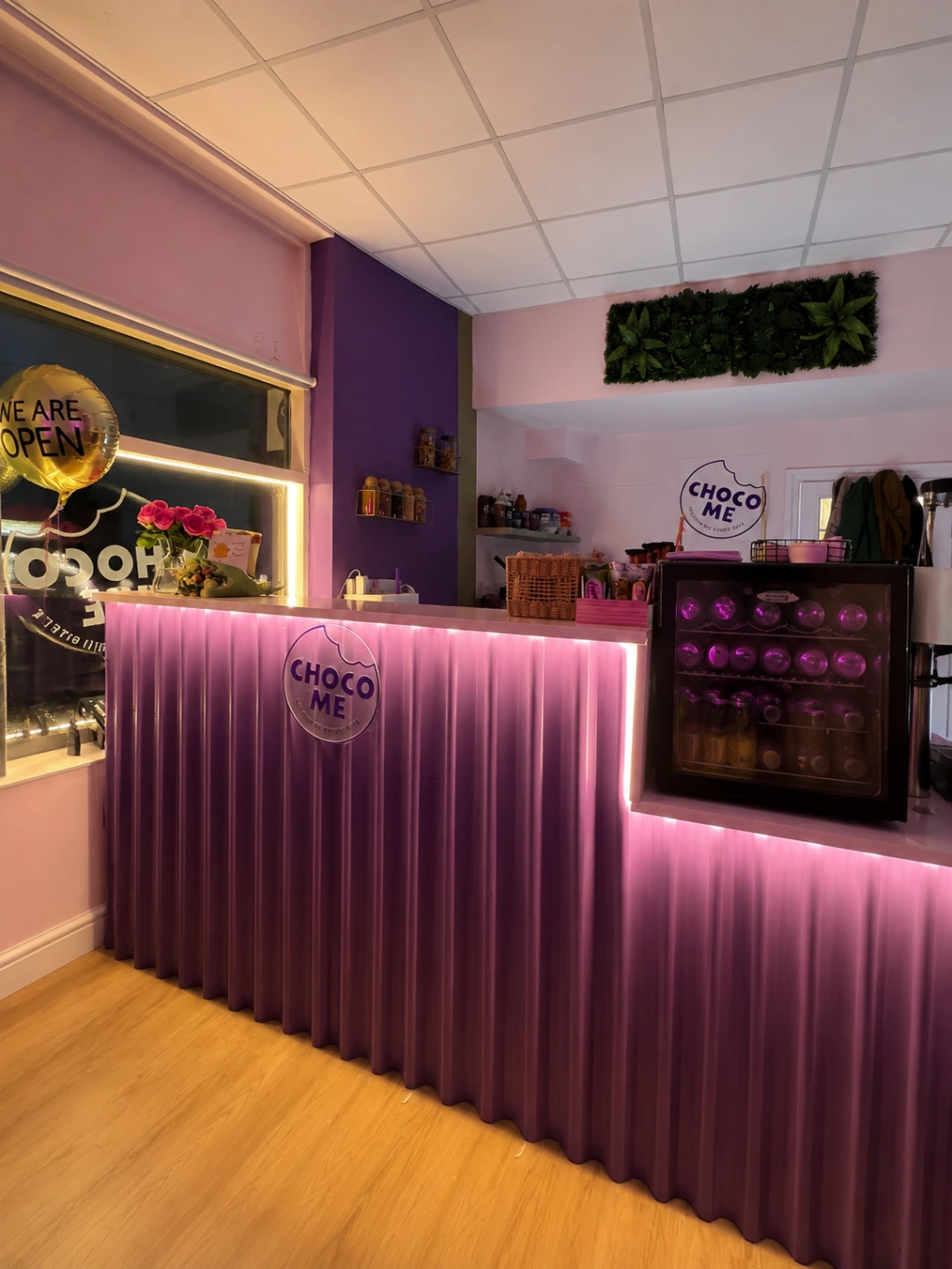 The statement counter combines fluted detailing, strategic lighting, and bold brand colours to create a premium customer experience on a limited budget. Purple fluted statement counter with integrated lighting, designed as the focal point of the Choco Me dessert shop interior.