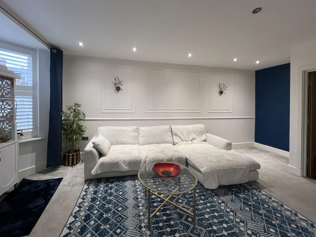 Modern luxury living room interior design by House of Ahana in Leeds Yorkshire UK featuring white sectional sofa, blue accent wall and designer rug