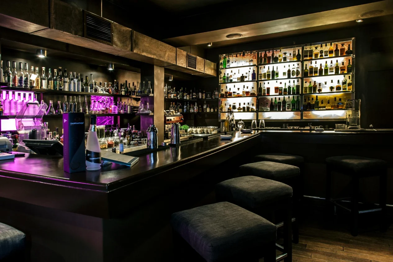 Luxury bar interior with backlit shelves, cocktail counter and ambient lighting in Birmingham UK